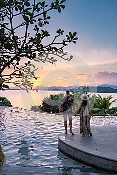 couple man and woman mid age in swimming pool on a luxury vacation in Thailand, men and Asian woman in pool looking out