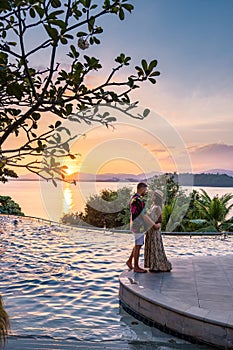 couple man and woman mid age in swimming pool on a luxury vacation in Thailand, men and Asian woman in pool looking out