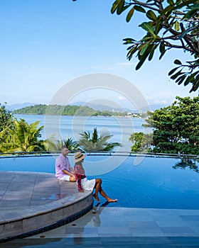 couple man and woman mid age in swimming pool on a luxury vacation in Thailand, men and Asian woman in pool looking out