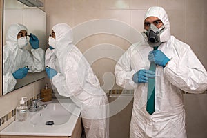 Couple of man and woman preparing to go out in the bathroom dressed in NBC portection suits during the covid 19 coronavirus crisis