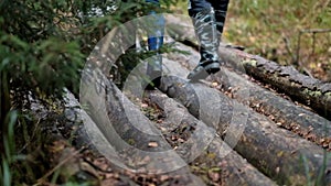 A couple, a man and a woman in rubber boots are walking through the forest.