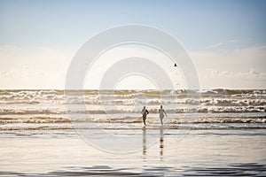 Couple of a man and a woman run to swim in the waves in the Northwest of the cold Pacific Ocean in the rays of the sun soluble in