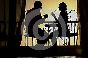 A Couple man and woman silhouette on a balcony by the sea on the background. Meeting in a double date on the terrace