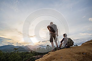 Couple Man and Woman sitting on cliff enjoying mountains, Travel