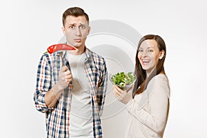 Couple, man, woman standing with green fresh salad in glass bowl, red hot chili pepper on fork isolated on white