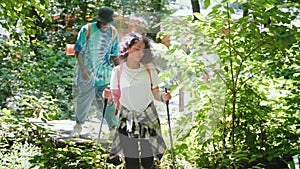 Couple man and woman with sticks trekking hiking in forest trail.