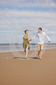 a couple of a man and a woman are walking on the beach or running along the sand along the seashore. beautiful and young