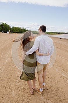 a couple of a man and a woman are walking on the beach or running along the sand along the seashore. beautiful and young