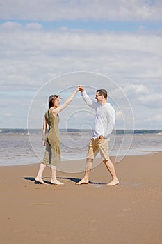 a couple of a man and a woman are walking on the beach or running along the sand along the seashore. beautiful and young