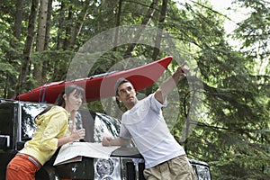 Couple With Map On Car Bonnet In Forest