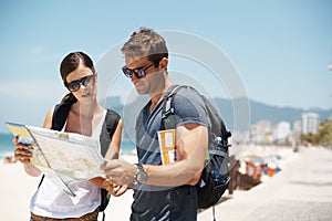 Couple, map and reading with direction at beach, summer and ideas to check path on vacation. Woman, man and chart for