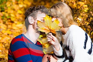 Couple with maple leaf kissing in autumn park