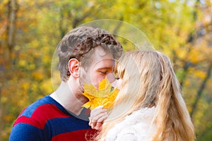 Couple with maple leaf kissing in autumn park