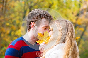 Couple with maple leaf kissing in autumn park