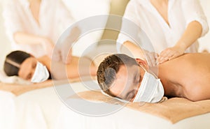 Couple in masks having back massage at spa