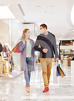 Couple in medical masks with shopping bags in mall