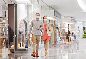 Couple in medical masks with shopping bags in mall