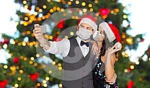 Couple in medical masks taking selfie on christmas