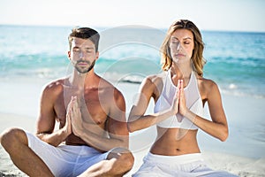 Couple meditating while sitting on shore