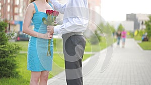 Couple meeting on a date, young man giving red rose to his beautiful girlfriend