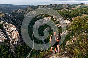 A couple meets the sunrise in the mountains, rear view. Man and woman in the mountains. Man and woman hugging. The couple travels