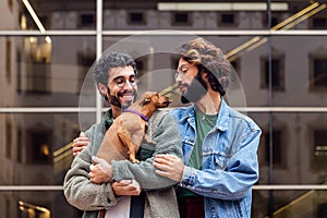 couple of men embracing with their loving little dog
