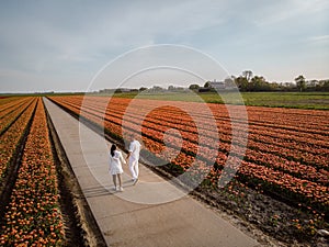 Couple men and woman in flower field in the Netherlands during Spring, orange red tulips field near Noordoostpolder