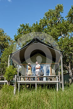 couple men and woman in front of safari tent on a luxury safary,South Africa, luxury safari lodge in the bush