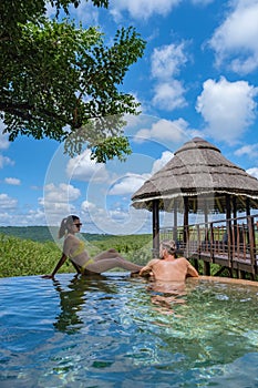 couple men and woman by the pool on a luxury safary,South Africa Kwazulu natal, luxury safari lodge in the bush