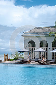 couple men and woman relaxing by the pool during a luxury vacation in Thailand