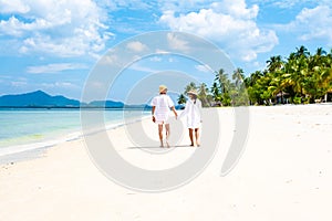 a couple of men and woman with summer hats walking at the beach of Koh Muk