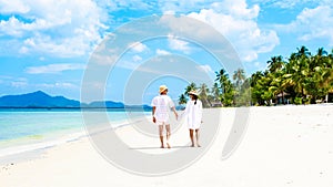 a couple of men and woman with summer hats walking at the beach of Koh Muk