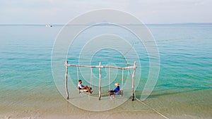 a couple of men and woman on a swing at the beach of Koh Muk Thailand