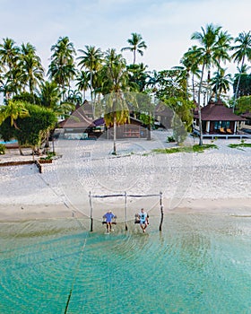 a couple of men and woman on a swing at the beach of Koh Muk Thailand