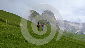 A couple of men and a woman visit the Dolomites Alps. Odle mountain range Seceda peak
