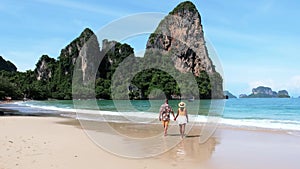 a couple of men and woman walking on the beach of Railay Beach Krabi Thailand