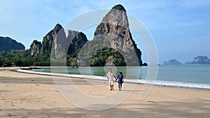 A couple of men and woman walking on the beach of Railay Beach Krabi Thailand