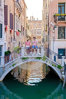 couple men and women on a city trip in Venice Italy sitting above a bridge at the canals of Venice