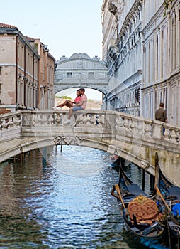 couple men and women on a city trip in Venice Italy sitting at a bridge above the canals of Venice