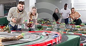 Couple, men and women play in childrens racing track