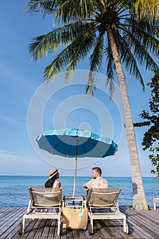 couple of men and women relaxing in beach bed looking out over the ocean under a umbrella