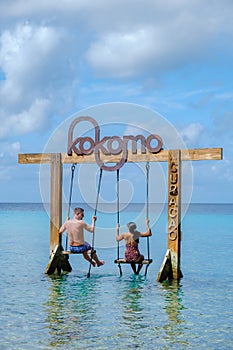 Couple at a swing in the ocean of Curacao Caribbean Island, Kokomo Beach Curacao photo