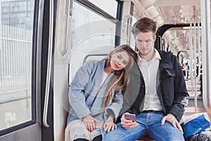 Couple in metro, young commuters sitting together photo