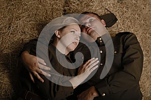 Couple in military uniforms from the second world war young woman and man lying in hayloft