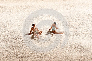 Couple of miniature people relaxing on a beach photo