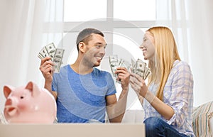 Couple with money and piggybank ot table at home