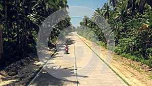 Couple, motorcycle and travel on road in a tropical island on street path between palm trees in nature. Man and woman
