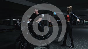 Couple and motorcycle in underground parking garage, woman puts on leather jacket