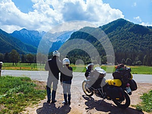 Couple of motorcyclists adventure riders. Green meadow in Zgornje Jezersko, to Kamnik-Savinja Alps on a sunny summer day in