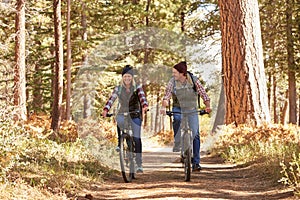 Couple mountain biking through forest, Big Bear, California photo
